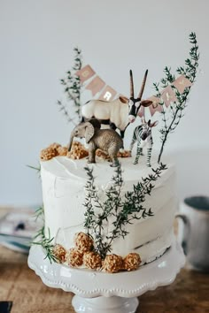 a white cake topped with an animal figurine on top of a wooden table