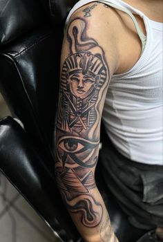 a person sitting in a chair with a tattoo on their arm and eye behind the arm