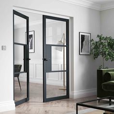 a living room with two doors and a green chair in the corner next to a potted plant