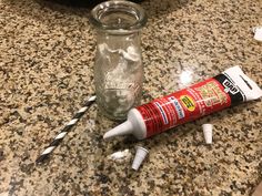 an empty glass bottle sitting on top of a counter next to some toothbrushes