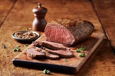 a piece of meat sitting on top of a cutting board next to some seasoning