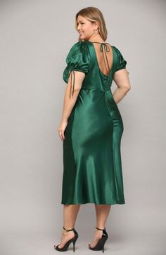 a woman wearing a green satin dress with open back and tie at the neckline