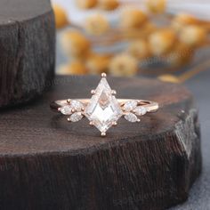 a white diamond ring sitting on top of a piece of wood with other items in the background