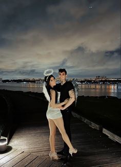 a man and woman posing for a photo in front of a body of water at night