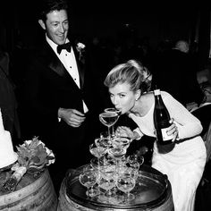 a man and woman are standing next to each other with wine glasses in front of them