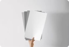 a person holding up three sheets of white paper