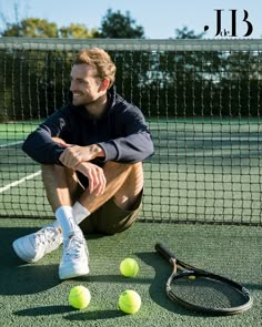 a man sitting on the ground with tennis balls and racket in front of him