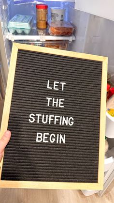 a sign that says let the stuffing begin in front of an open refrigerator with food inside