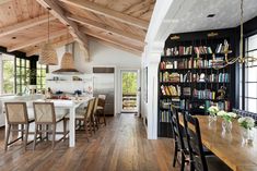 a large open kitchen and dining room area with wooden flooring, white walls and ceiling