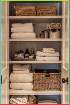 an organized closet with white linens, towels and baskets on the shelve