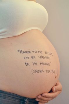 a pregnant woman holding her belly with writing on it's side, in spanish