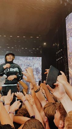 a man standing on top of a stage surrounded by lots of people holding cell phones