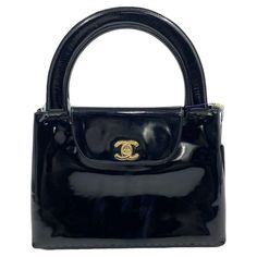 Own a Parisian dream: Vintage Chanel Kelly in black patent leather. This iconic bag exudes timeless elegance, with high-shine patent reflecting years of love (and light wear). 24k gold plated hardware adds a touch of Parisian luxury, while subtle age marks whisper tales of glamorous adventures. The Chanel Kelly reissued in 2023 is the IT bag of the year, and this vintage model lets you own the style with a steal of a price. Carry it by hand or on your arm to elevate any outfit and embrace the timeless beauty of Chanel. Vintage Chanel Kelly Black patent leather 24k gold plated hardware Width: 25cm Height: 17cm Chanel Bag Top Handle, Luxury Black Patent Leather Shoulder Bag, Luxury Black Glossy Finish Shoulder Bag, Luxury Black Patent Leather Bag, Elegant Patent Leather Evening Bags, Classic Evening Bags In Patent Leather, Classic Patent Leather Evening Bags, Evening Bags With Detachable Handle In Patent Leather, Luxury Patent Leather Bags For Formal Occasions