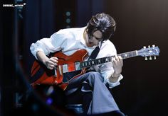 a man playing an electric guitar while wearing a white shirt and black tie on stage