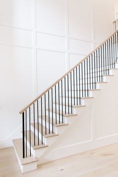 a white staircase with black handrails in an empty room next to a wall