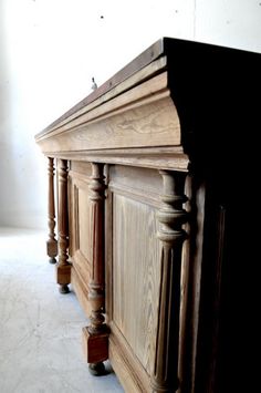 an old wooden dresser with wood carvings on the top and bottom, sitting in a white room