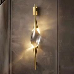 a wall light that is on the side of a metal door with a glass vase in front of it