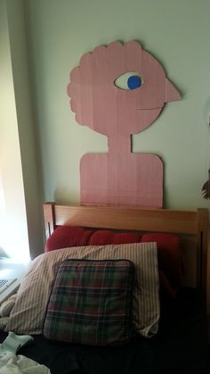 a bed with pillows and a wooden headboard made to look like an eyeball