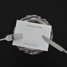 there is a fork and knife on top of a plate with a piece of paper