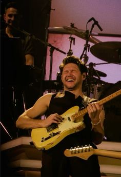 a man is laughing while playing an electric guitar