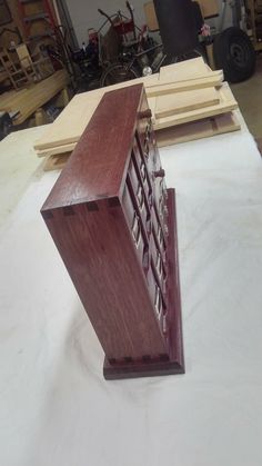 a wooden clock sitting on top of a piece of plywood in a workshop area