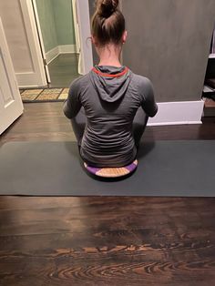 a woman sitting on top of a yoga mat with her back to the camera,