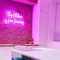 the kitchen is for dancing with neon lights and stools in front of the counter