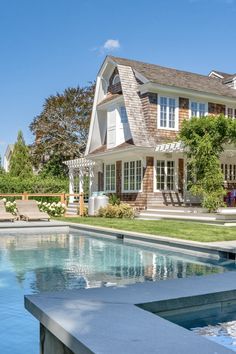 a pool in front of a large house with a patio and swimming pool next to it