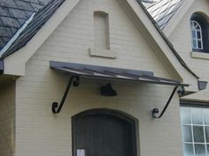 a white brick house with a black door and metal brackets on the side of it