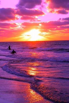 two surfers in the ocean at sunset