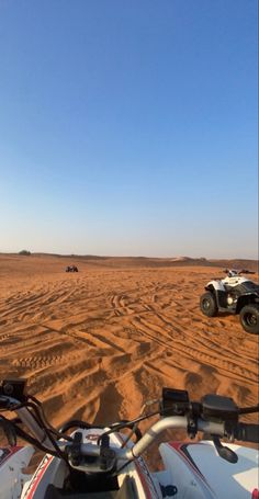 two vehicles driving in the desert on a sunny day