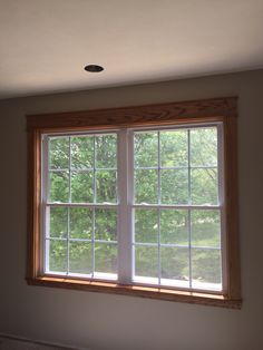 an empty room with a large window and no curtains on the windowsill, in front of some trees