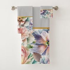 two towels hanging on a towel rack next to each other with flowers painted on them