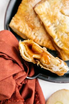 some food is on a black plate and next to an apple pie with caramel sauce