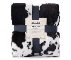 the black and white cow print blanket is wrapped up in a gift box with a tag that says faux fur throw