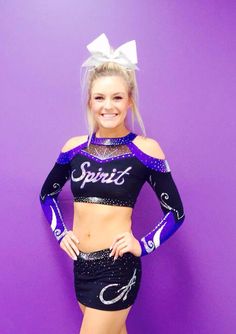 a beautiful young woman in a black and purple outfit posing for the camera with her hands on her hips