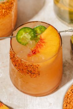 two glasses filled with drinks and garnishes on top of a table next to limes