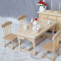 a dollhouse table and chairs set up with flowers in vases on the side