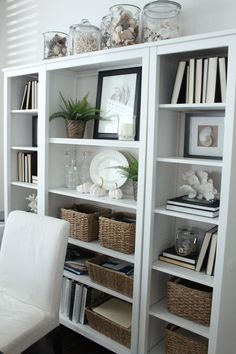 a white chair sitting in front of a book shelf filled with books and other items