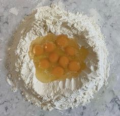 flour and eggs in a bowl on a marble counter top, ready to be mixed