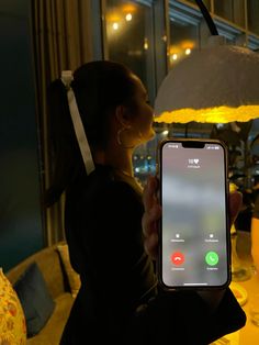 a woman holding up an iphone in front of a table with food and drinks on it