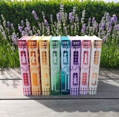 four books are stacked on top of each other in front of some lavenders and flowers