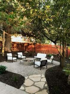 an outdoor fire pit surrounded by chairs and trees