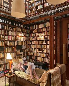 a man laying on top of a couch in front of a book shelf filled with books