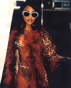 a woman in a leopard print outfit with sunglasses on her head and fur coat over her shoulders