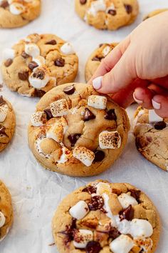 someone picking up some cookies with marshmallows on them