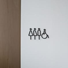 three metal figures on a white wall next to a wooden door with the word family spelled in black