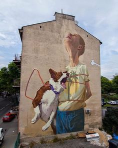 a painting on the side of a building with a dog and man holding a leash