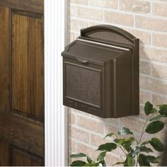 a mailbox mounted to the side of a brick wall next to a potted plant