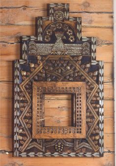 an ornate wooden frame hanging on the side of a wood paneled wall with decorative designs